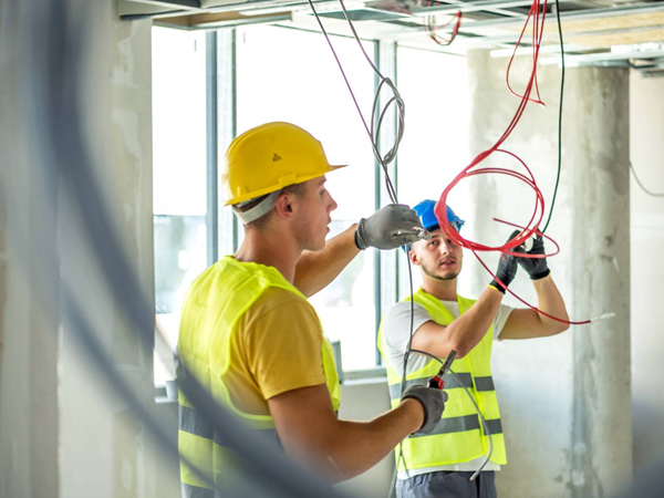 imagem com dois eletricistas da Gallo Construtora fazendo instalação eletrica em uma residencia