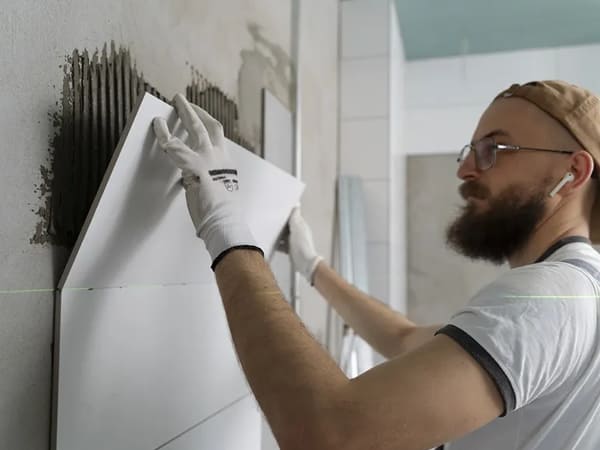 imagem com um especialista de revestimento da Gallo Construções e Reformas colocando revestimento na parede de uma cozinha