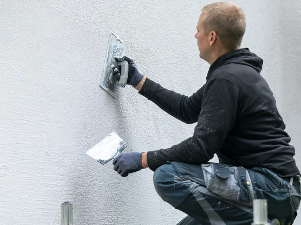 imagem com um profissional da Gallo Construções e Reformas aplicando gesso em uma parede